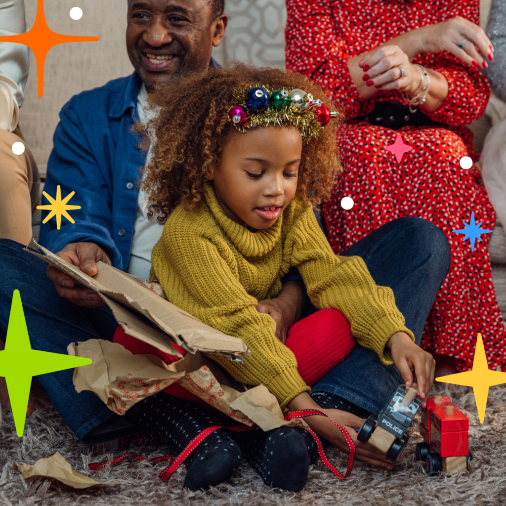 Girl unwrapping Christmas present with family
