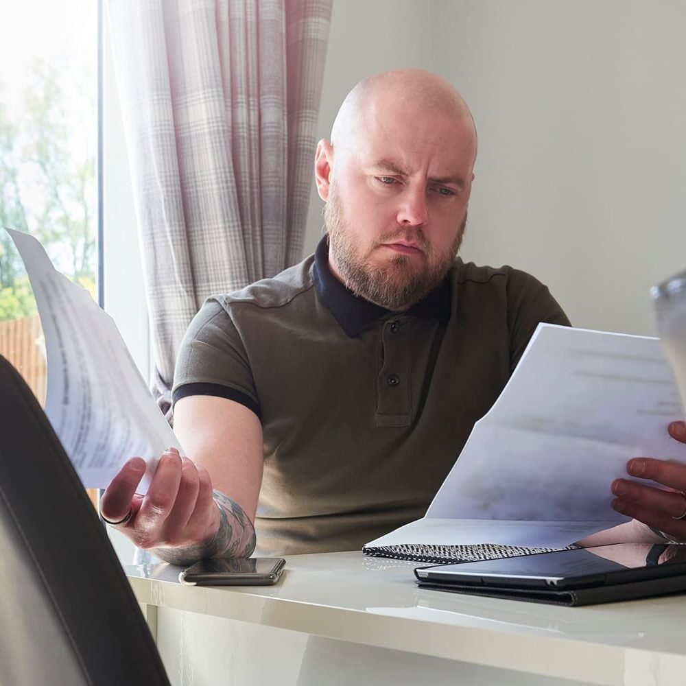 frowning man sits at the table looking through bills