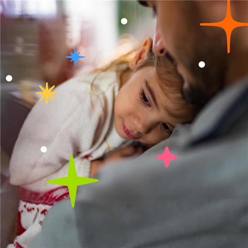 Little girl in Christmas jumper looking sad being held by her dad comforting her